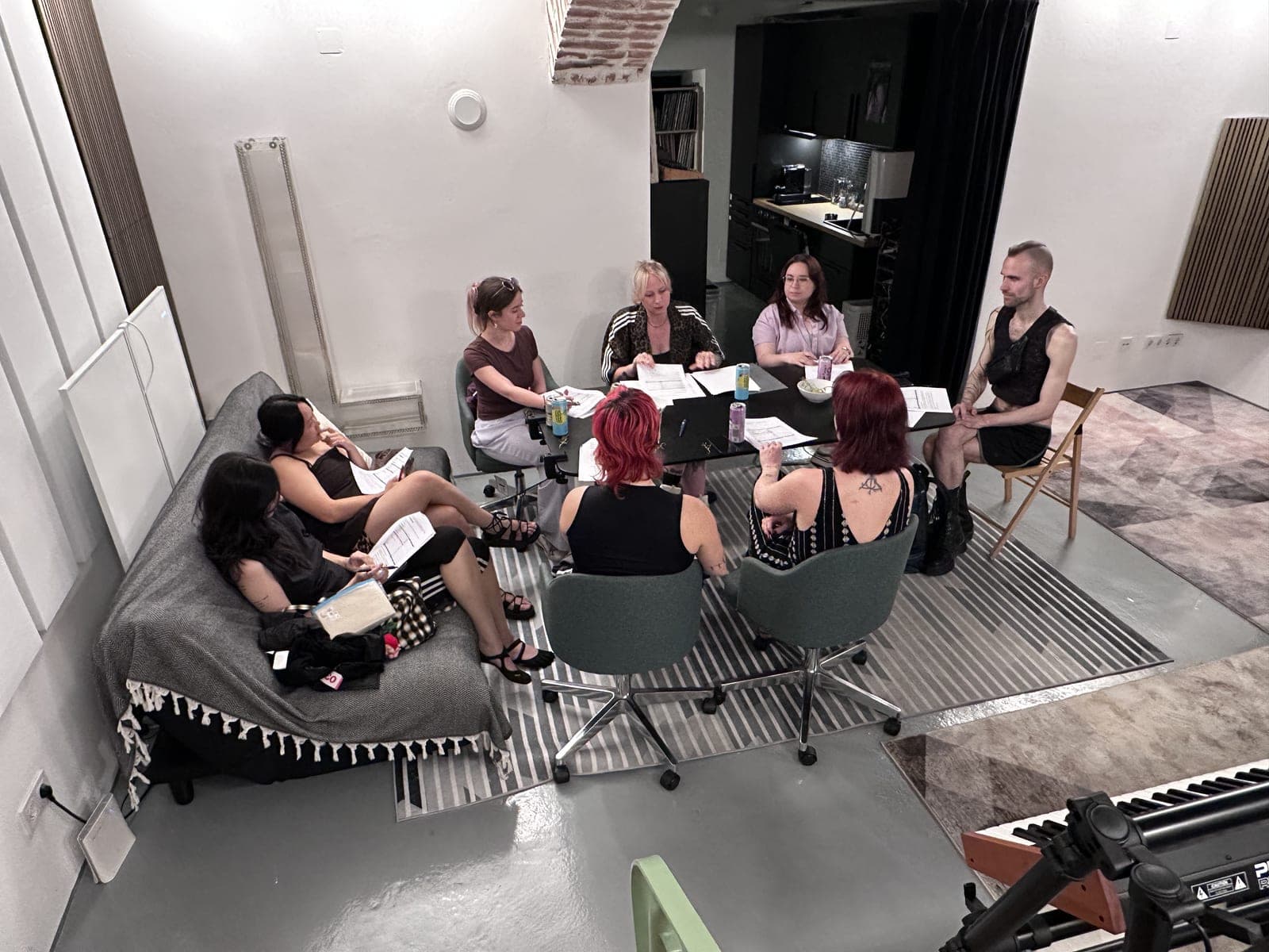 Eine Kursrunde im Studio: Menschen sitzen im Kreis und arbeiten mit Unterlagen.
